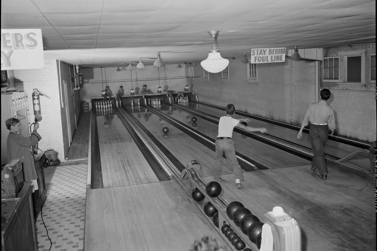 Salle de bowling de quatre pistes en 1946, avec des requilleurs manuels au fond des pistes